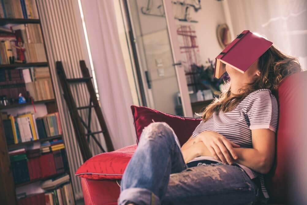 How to spend your free time Woman sits on the sofa with a book on her face
