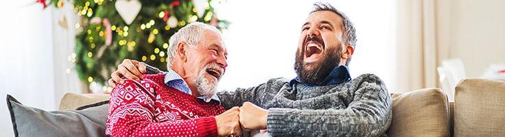 Två män som skrattar vid en julgran