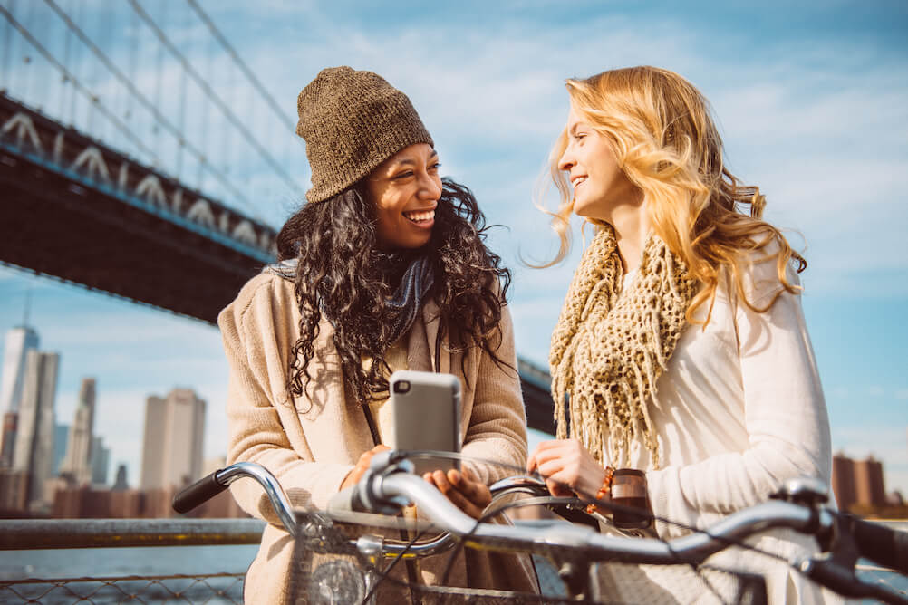 Two women looking at a map on their phone to find the best European lottos